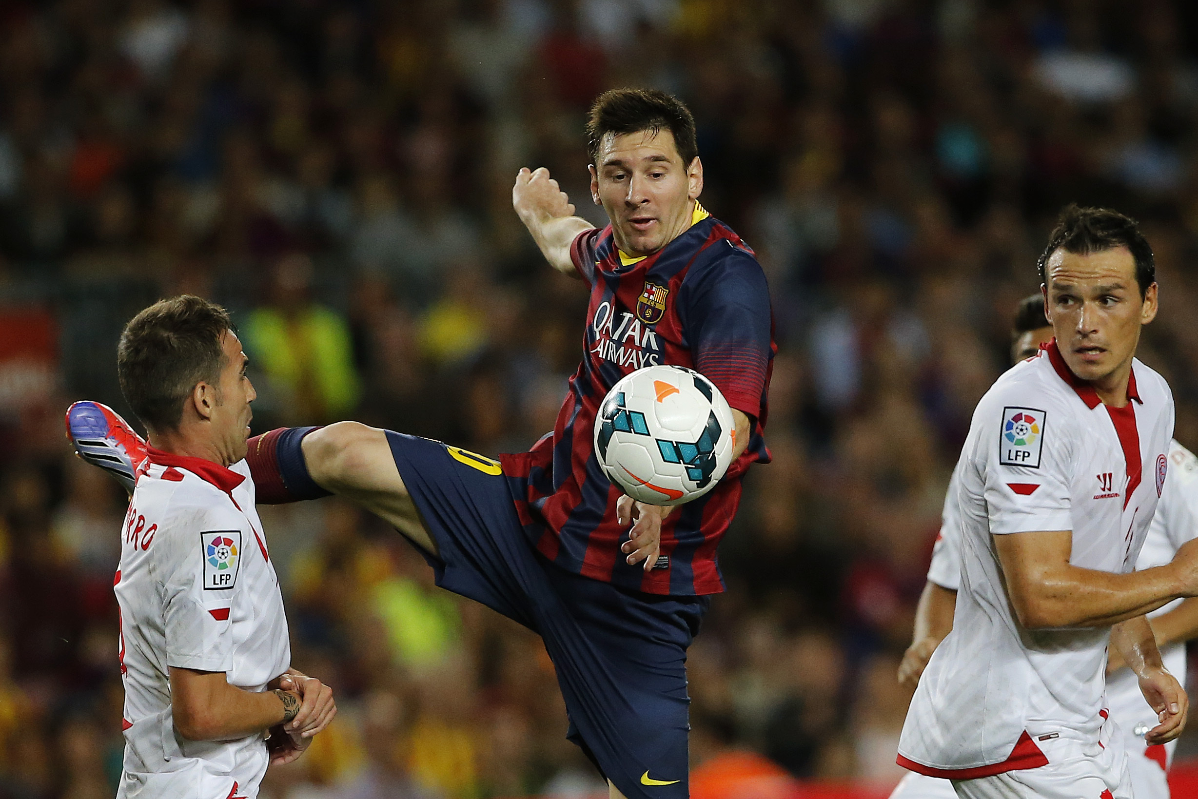 FC Barcelona's Lionel Messi from Argentina, in action with Sevilla's Fernando Navarro, left, and Piotr Trochowski from Poland, right, during a Spanish La Liga soccer match at the Camp Nou stadium in Barcelona, Spain, Saturday, Sept. 14, 2013. (AP Photo/Emilio Morenatti)