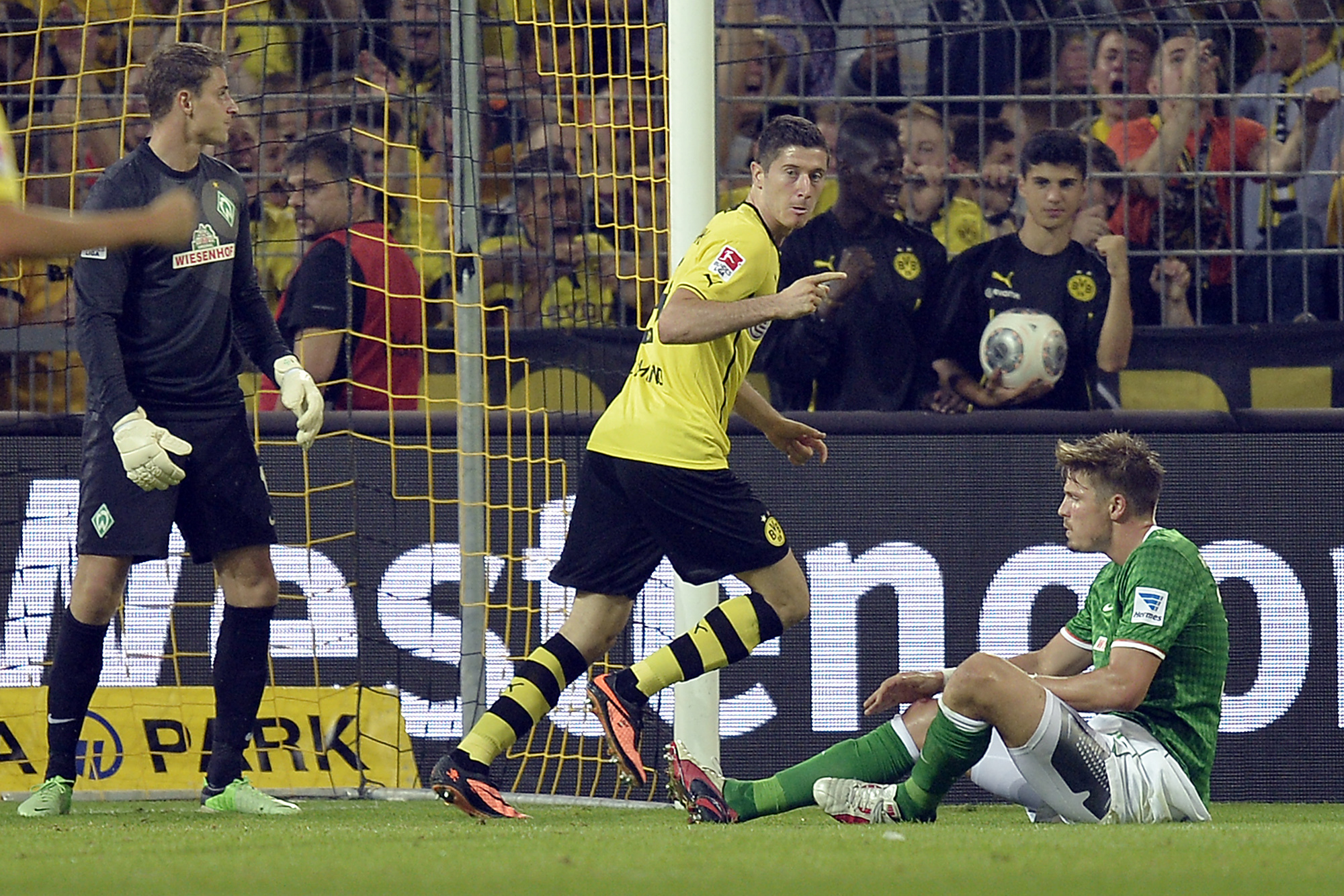 Dortmund's Robert Lewandowski of Poland, center, reacts after scoring the opening goal against Bremen goalkeeper Sebastian Mielitz, left, Sebastian Proedl of Austria right, during the German soccer Bundesliga match between Borussia Dortmund and Werder Bremen in Dortmund, Germany, Friday, Aug. 23, 2013. (AP Photo/Martin Meissner)