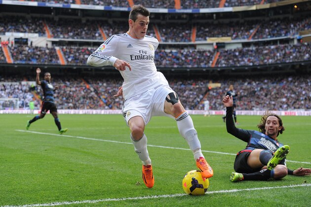 MADRID, SPAIN - JANUARY 25:  Gareth Bale (L) of Real Madrid CF tries to beat Manuel Iturra of Granada CF during the La Liga match between Real Madrid CF and Granada CF at Santiago Bernabeu stadium on January 25, 2014 in Madrid, Spain.  (Photo by Denis Doyle/Getty Images)