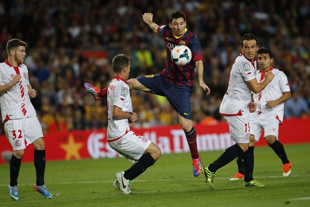 FC Barcelona's Lionel Messi from Argentina, center, in action with Sevilla's Fernando Navarro, left, and Piotr Trochowski from Poland, right, during a Spanish La Liga soccer match at the Camp Nou stadium in Barcelona, Spain, Saturday, Sept. 14, 2013. (AP Photo/Emilio Morenatti)