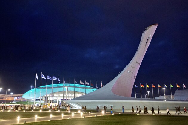 Spectators walk by the Bolshoy Ice Dome at left and the Olympic cauldron on their way to the rehearsal of the opening ceremony at the 2014 Winter Olympics, Saturday, Feb. 1, 2014, in Sochi, Russia. (AP Photo/David Goldman)