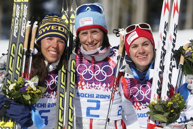 Norway's gold medal winner Marit Bjoergen is flanked by Sweden's silver medal winner Charlotte Kalla, left, and Norway's bronze medal winner Heidi Weng after the flower ceremony for the women's cross-country 15k skiathlon at the 2014 Winter Olympics, Saturday, Feb. 8, 2014, in Krasnaya Polyana, Russia. (AP Photo/Dmitry Lovetsky)