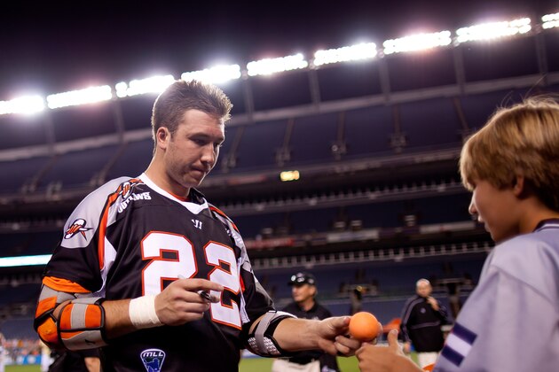 DENVER, CO - JUNE 16:  Mark Matthews #22 of the Denver Outlaws signs an autograph for a ball boy after a game against the Rochester Rattlers at Sports Authority Field at Mile High on June 16, 2012 in Denver, Colorado. The Outlaws defeated the Rattlers 16-12.  (Photo by Justin Edmonds/Getty Images)