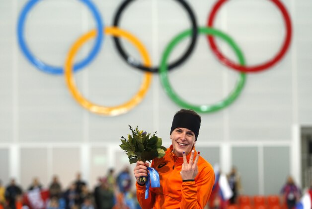 Ireen Wust of the Netherlands flashes three fingers indicating her third olympic gold medal, during the flower ceremony after winning gold in the women's 3,000-meter speedskating race at the Adler Arena Skating Center during the 2014 Winter Olympics, Sunday, Feb. 9, 2014, in Sochi, Russia.  (AP Photo/Pavel Golovkin)