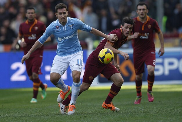 Lazio's Miroslav Klose, left, and AS Roma midfielder Alessandro Florenzi vie for the ball  during an Italian Serie A soccer match between Lazio and AS Roma at Rome's Olympic stadium, Sunday, Feb. 9, 2014. (AP Photo/Alessandra Tarantino)