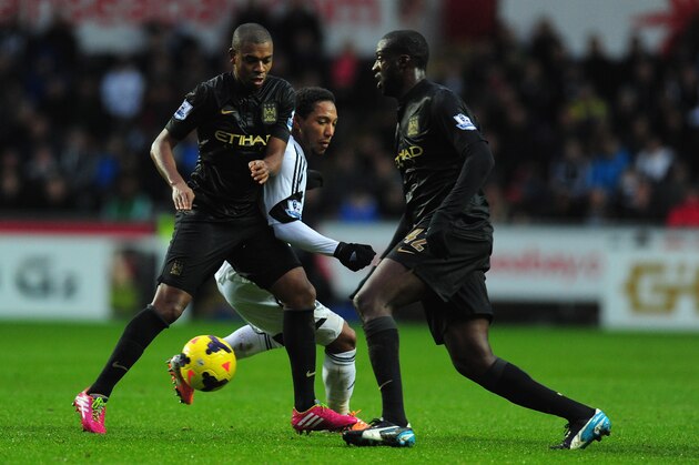 SWANSEA, WALES - JANUARY 01:  Manchester City players Fernandinho (l) and Yaya Toure (r) combine to halt Jonathan de Guzman during the Barclays Premier League match between Swansea City and Manchester City at Liberty Stadium on January 1, 2014 in Swansea, Wales.  (Photo by Stu Forster/Getty Images)