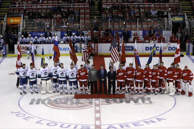 Members of the Vancouver Canucks and the Detroit Red Wings who are playing in the Olympics pose at center ice before the first period of an NHL hockey game in Detroit, Monday, Feb. 3, 2014. (AP Photo/Carlos Osorio)