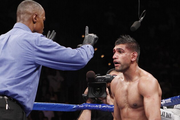 Amir Khan, of England, is counted to by referee Kenny Bayless, left, after being knocked down by Danny Garcia, of the United States, during their WBC and WBA junior welterweight title boxing match, Saturday, July 14, 2012, in Las Vegas. Garcia won by a fourth round TKO victory. (AP Photo/Eric Jamison)