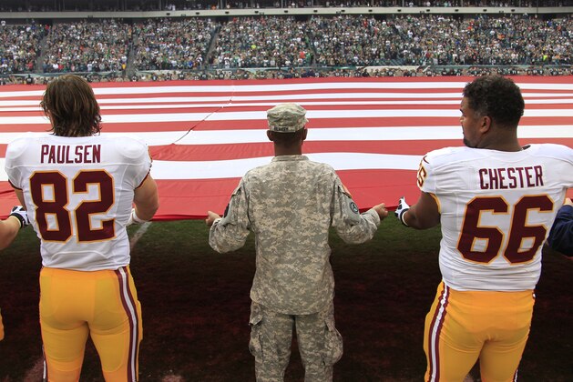 Washington Redskins tight end Logan Paulsen and guard Chris Chester, right, help hold the U.S. flag before an NFL football game between the Philadelphia Eagles and the Washington Redskins in Philadelphia, Sunday, Nov. 17, 2013. (AP Photo/Matt Rourke)