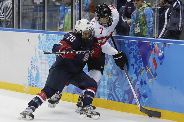 Amanda Kessel of the Untied States traps Lara Stalder of Switzerland up against the boards during the 2014 Winter Olympics women's ice hockey game at Shayba Arena, Monday, Feb. 10, 2014, in Sochi, Russia. USA defeated Switzerland 9-0. (AP Photo/Matt Slocum)