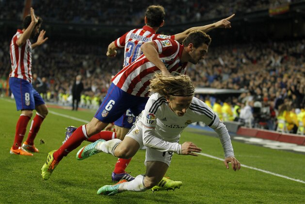 Real's Luka Modric, right is pushed to the ground during a semi final, 1st leg, Copa del Rey soccer derby match between Real Madrid and Atletico Madrid at the Santiago Bernabeu Stadium in Madrid, Wednesday Feb. 5, 2014.  (AP Photo/Paul White)