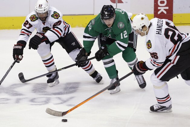 Dallas Stars right wing Alex Chiasson (12) skates for the puck against Chicago Blackhawks center Michal Handzus (26) and defenseman Johnny Oduya (27) during the first period of an NHL hockey game Friday, Nov. 29, 2013, in Dallas. (AP Photo/LM Otero)