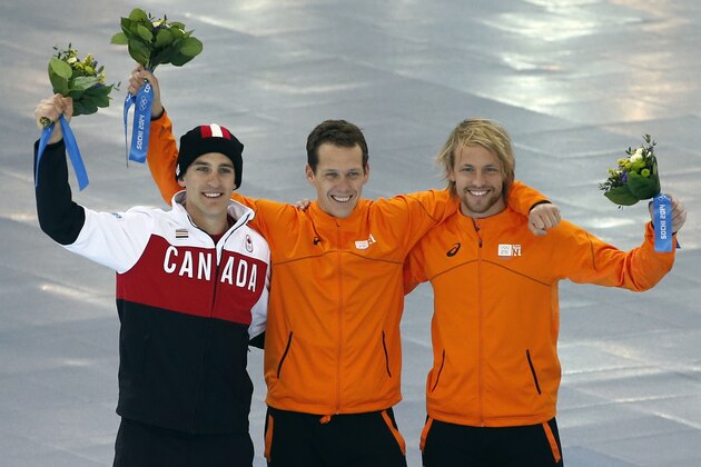 Silver medallist Canada's Denny Morrison, left, agold medallist Stefan Groothuis of the Netherlands, center, and bronze medallist Michel Mulder of the Netherlands, celebrate during the flower ceremony for the men's 1000-meter speedskating race at the Adler Arena Skating Center during the 2014 Winter Olympics in Sochi, Russia, Wednesday, Feb. 12, 2014. (AP Photo/Pavel Golovkin)