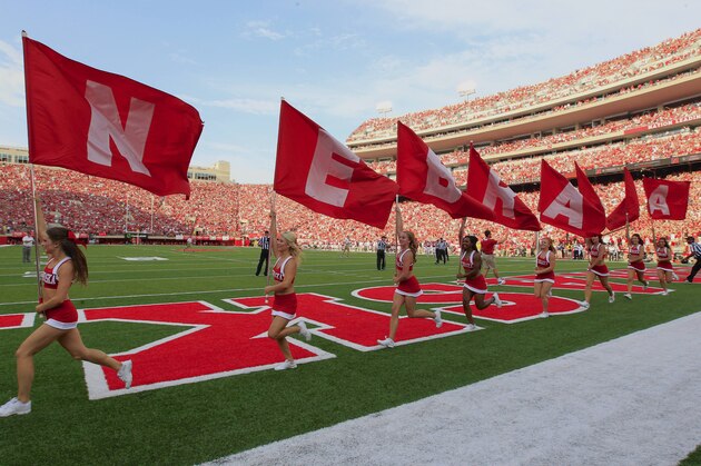 Nebraska cheerleaders run with flags at Memorial Stadium after a score against Southern Mississippi in the first half of an NCAA college football game in Lincoln, Neb., Saturday, Sept. 7, 2013. (AP Photo/Nati Harnik)