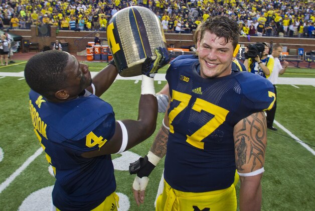 Michigan linebacker Cameron Gordon (4), and offensive lineman Taylor Lewan (77) celebrate with the Little Brown Jug trophy after an NCAA college football game with Minnesota, Saturday, Oct. 5, 2013, in Ann Arbor, Mich. Michigan retains the rivalry trophy after winning 42-13. (AP Photo/Tony Ding)