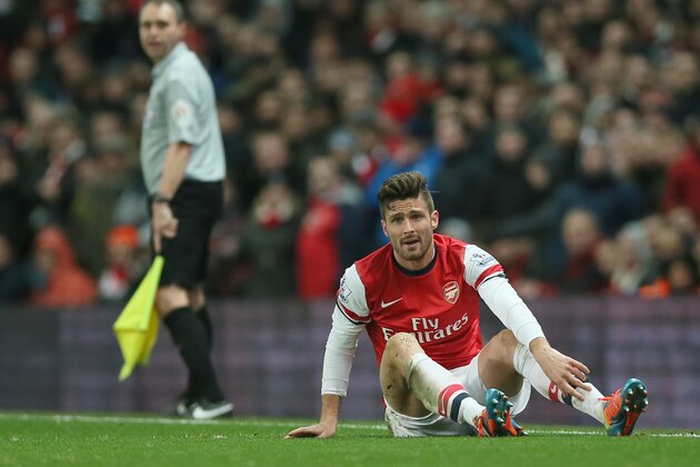 Arsenal Oliver Giroud lies on the ground following a hard tackle during the English Premier League soccer match between Arsenal and Manchester United at the Emirates stadium in London, Wednesday, Feb. 12, 2014.The game ended 0-0 draw.  (AP Photo/Alastair Grant)