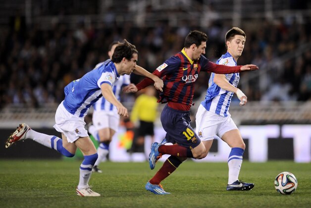 FC Barcelona's Lionel Messi of Argentina, center, goes for the ball between Real Sociedad's Jon Gaztanaga, right, and Mikel Gonzalez, left, before to scoring his goal, during their Spanish Copa del Rey semifinal second leg soccer match, at Anoeta stadium, in San Sebastian northern Spain, Wednesday, Feb. 12, 2014. (AP Photo/Alvaro Barrientos)