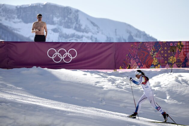 A shirtless spectator watches Sweden's Charlotte Kalla compete during the women's 10K classical-style cross-country race at the 2014 Winter Olympics, Thursday, Feb. 13, 2014, in Krasnaya Polyana, Russia. Kalla won the silver medal. (AP Photo/Jae C. Hong)