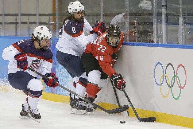 Michelle Picard (3) and Megan Bozek (9) of the United States battle Hayley Wickenheiser (22) of Canada for control of the puck during the 2014 Winter Olympics women's ice hockey game at Shayba Arena, Wednesday, Feb. 12, 2014, in Sochi, Russia. (AP Photo/Matt Slocum)