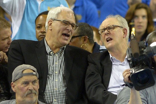 Former NBA coach Phil Jackson, left, and actor John Lithgow talk as they watch UCLA play Arizona during the first half of an NCAA college basketball game, Thursday, Jan. 9, 2014, in Los Angeles. (AP Photo/Mark J. Terrill)