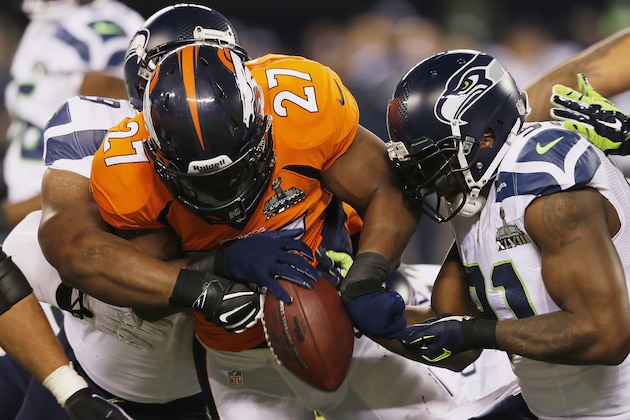 EAST RUTHERFORD, NJ - FEBRUARY 02:  Running back Knowshon Moreno #27 of the Denver Broncos is tackled by defensive tackle Clinton McDonald #69 and defensive end Chris Clemons #91 of the Seattle Seahawks in the first half during Super Bowl XLVIII at MetLife Stadium on February 2, 2014 in East Rutherford, New Jersey.  (Photo by Kevin C. Cox/Getty Images)