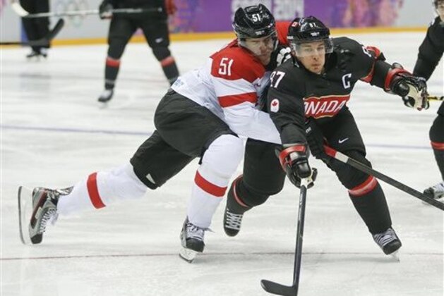 Canada forward Sidney Crosby gets tangled up with Latvia forward Koba Jass in the first period of a men's ice hockey game at the 2014 Winter Olympics, Friday, Feb. 14, 2014, in Sochi, Russia. (AP Photo/Mark Humphrey)