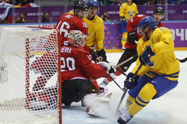 Sweden forward Daniel Alfredsson scores a goal against Switzerland goaltender Reto Berra in the third period of a men's ice hockey game at the 2014 Winter Olympics, Friday, Feb. 14, 2014, in Sochi, Russia. (AP Photo/Mark Humphrey)