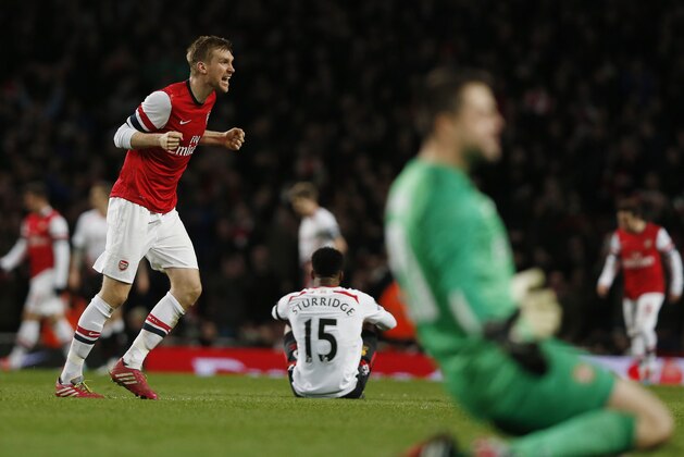 Arsenal's Per Mertesacker, left, and goalkeeper Lukasz Fabianski, right foreground, celebrate their win as Liverpool's Daniel Sturridge, center, sits on the ground at the end of their English FA Cup fifth round soccer match at Emirates Stadium in London, Sunday, Feb. 16, 2014. (AP Photo/Sang Tan)