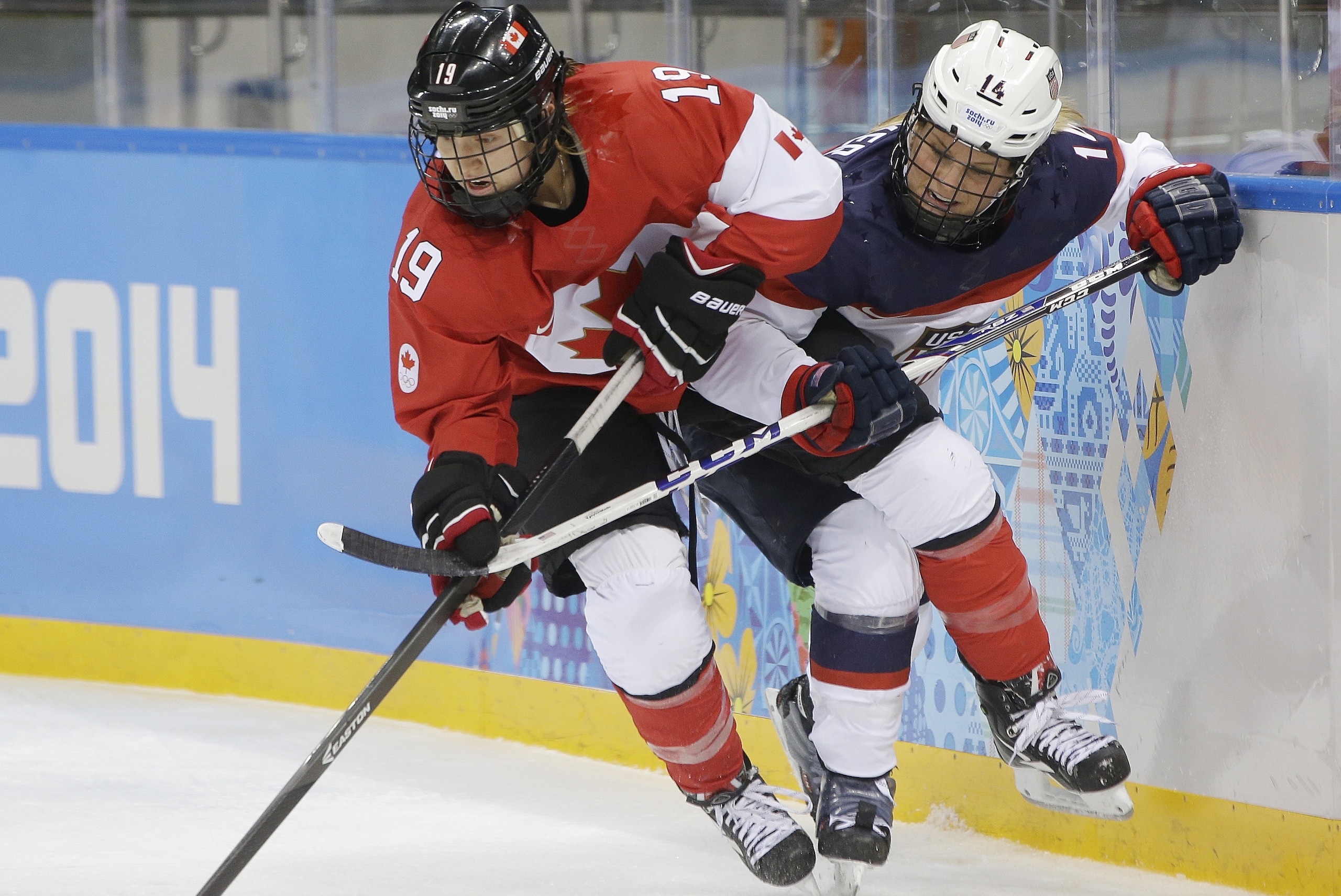 Brianne Jenner of Canada and Brianna Decker of the United States battle up again the boards for control of the puck during the second period of the 2014 Winter Olympics women's ice hockey game at Shayba Arena, Wednesday, Feb. 12, 2014, in Sochi, Russia. (AP Photo/Matt Slocum)