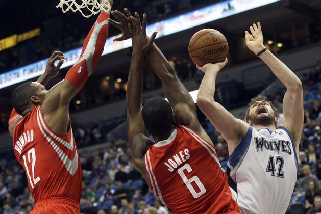 Minnesota Timberwolves' Kevin Love, right, attempts a shot as Houston Rockets' Dwight Howard, left, and Terrence Jones defend in the first quarter of an NBA basketball game, Monday, Feb. 10, 2014, in Minneapolis. (AP Photo/Jim Mone)