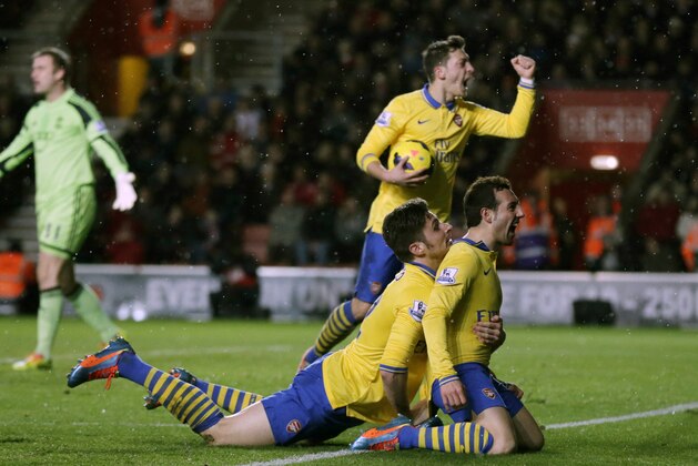 Arsenal's Santi Cazorla, bottom right, celebrates his goal with Olivier Giroud, bottom left, and Mesut Ozil as Southampton's goalkeeper Artur Boruc holds his arms out in frustration during the English Premier League soccer match between Southampton and Arsenal at St Mary's stadium in Southampton, Tuesday, Jan. 28, 2014.  (AP Photo/Matt Dunham)