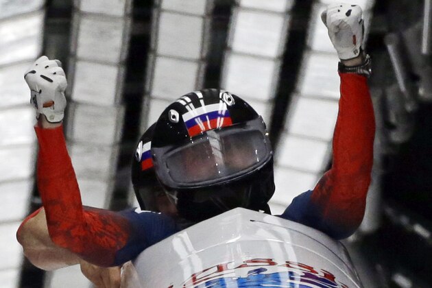The team from Russia RUS-1, piloted by Alexander Zubkov and brakeman Alexey Voevoda, cross into the finish area to win the gold medal during the men's two-man bobsled competition at the 2014 Winter Olympics, Monday, Feb. 17, 2014, in Krasnaya Polyana, Russia. (AP Photo/Dita Alangkara)