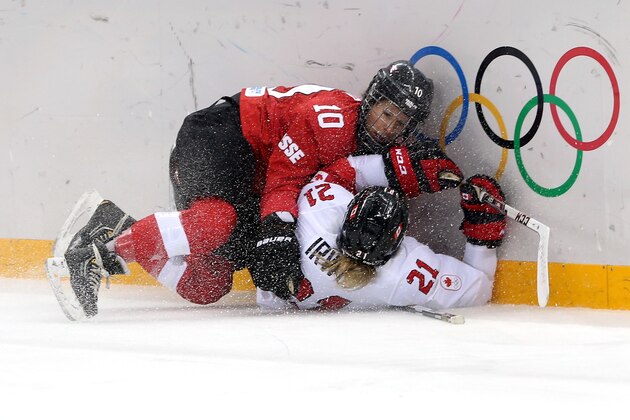 SOCHI, RUSSIA - FEBRUARY 17:  Nicole Bullo #10 of Switzerland and Haley Irwin #21 of Canada crash into the boards during the Women's Ice Hockey Playoffs Semifinal game on day ten of the Sochi 2014 Winter Olympics at Shayba Arena on February 17, 2014 in Sochi, Russia.  (Photo by Bruce Bennett/Getty Images)