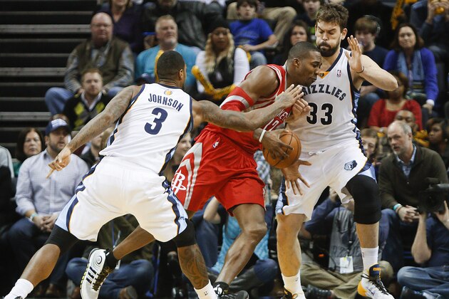 Houston Rockets center Dwight Howard (12) drives to the basket against Memphis Grizzlies forward James Johnson (3) and center Marc Gasol (33) in the second half of an NBA basketball game Saturday, Jan. 25, 2014, in Memphis, Tenn. The Grizzlies won 99-81. (AP Photo/Lance Murphey)
