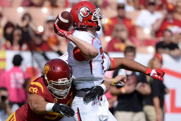 Oct 26, 2013; Los Angeles, CA, USA; Utah Utes quarterback Travis Wilson (7) is hit as by USC Trojans defensive end J.R. Tavai (58) as he throws a pass during first quarter action at Los Angeles Memorial Coliseum. Mandatory Credit: Robert Hanashiro-USA TODAY Sports