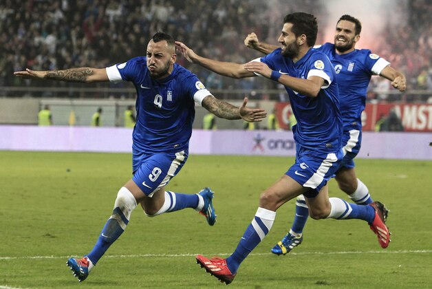 Greece's Kostas Mitroglou, left, celebrates after scoring the third goal of his team against Romania during their World Cup qualifying playoff first leg soccer match at the Karaiskaki stadium in the port of Piraeus, near Athens, Friday, Nov. 15, 2013. (AP Photo/Thanassis Stavrakis)