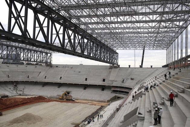 Journalists overlook construction of the Arena da Baixada stadium, in Curitiba, Brazil, Saturday, Dec.14, 2013. Workers went on strike over late pay at one of the stadiums enduring the longest delays ahead of the World Cup in Brazil, officials said Saturday. The work stoppage happened in the southern city of Curitiba, where world champion Spain is expected to be based during football's showcase event next year. (AP Photo/Renata Brito)