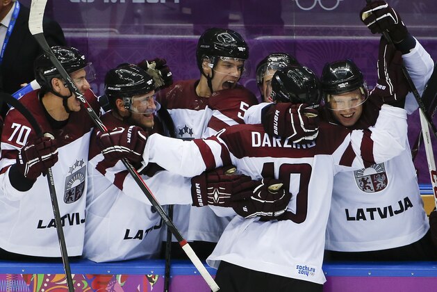 Latvia forward Lauris Darzins is congratulated by teammates after scoring against Switzerland in the third period of a men's ice hockey game at the 2014 Winter Olympics, Tuesday, Feb. 18, 2014, in Sochi, Russia. Latvia won 3-1 to advance to the quarterfinals. (AP Photo/Julio Cortez)