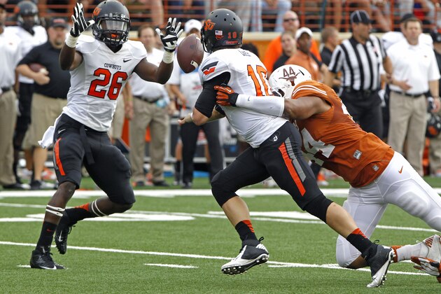 Oklahoma State quarterback Clint Chelf (10) is hit by Texas defensive lineman Jackson Jeffcoat (44) as he flips the ball to running back Desmond Roland (26) during the first quarter of an NCAA college football game Saturday, Nov. 16, 2013, in Austin, Texas. (AP Photo/Michael Thomas)