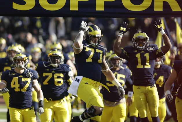 Michigan offensive linesman Taylor Lewan (77) and cornerback Courtney Avery (11) lead the team as they enter the stadium before the first quarter of an NCAA college football game against Ohio State in Ann Arbor, Mich., Saturday, Nov. 30, 2013. (AP Photo/Carlos Osorio)