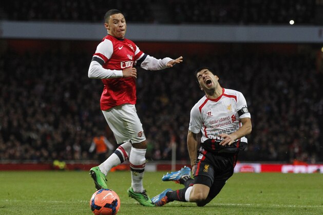 Liverpool's Luis Suarez, right, is tackled by Arsenal's Alex Oxlade-Chamberlain during their English FA Cup fifth round soccer match at Emirates Stadium in London, Sunday, Feb. 16, 2014. (AP Photo/Sang Tan)