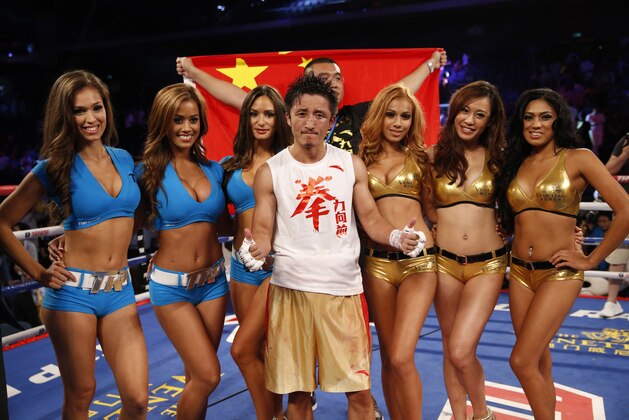 In this  July 27, 2013 photo, Chinese boxer Zou Shiming, front center, poses with ring girls before the Flyweight bout match against Mexico's Jesus Ortega at the Cotai Arena in Venetian Macao in Macau. The Chinese fighter’s victory at a Macau showdown brings the world’s top casino market a step closer to challenging Las Vegas for dominance of another Sin City staple: big-time boxing matches. Macau, which long ago eclipsed Vegas as the world's top gambling city, is now looking to add to its allure by holding the kind of boxing bouts that Las Vegas is known for. (AP Photo/Dennis Ho)