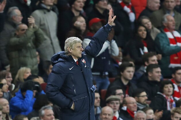 Arsenal's manager Arsene Wenger tries to get the attention of the referee for a substitution as he watches his team play against Liverpool during their English FA Cup fifth round soccer match at Emirates Stadium in London, Sunday, Feb. 16, 2014. (AP Photo/Sang Tan)