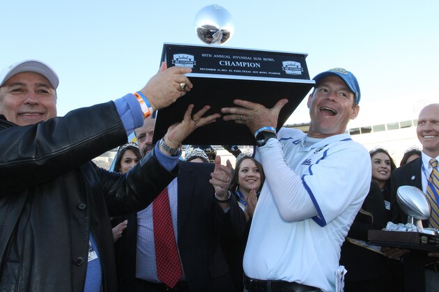 UCLA head football coach Jim Mora, right, and athletic director Dan Guerrero held up the Sun Bowl championship trophy after defeating Virginia Tech 42-12 in an NCAA college football game Tuesday Dec. 31, 2013, in El Paso, Texas. (AP Photo/Victor Calzada)