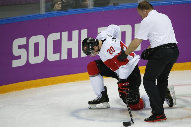 Canada forward John Tavares is helped up off the ice by a trainer during the second period of a men's quarterfinal ice hockey game against Latvia at the 2014 Winter Olympics, Wednesday, Feb. 19, 2014, in Sochi, Russia. Tavares is out for the rest of the Olympics with an unspecified leg injury. (AP Photo/Mark Humphrey)