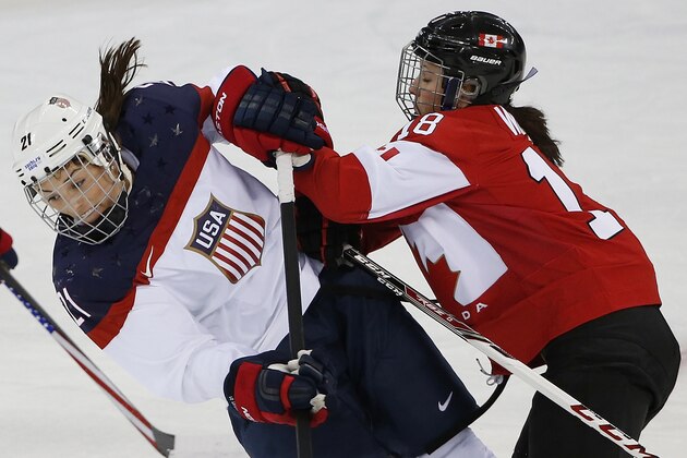 Hilary Knight of the United States collides with Catherine Ward of Canada during the first quarter of the 2014 Winter Olympics women's ice hockey game at Shayba Arena, Wednesday, Feb. 12, 2014, in Sochi, Russia. (AP Photo/Petr David Josek)
