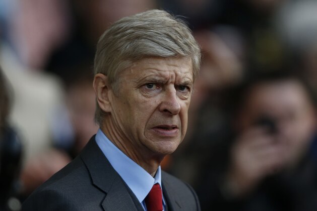 Arsenal's manager Arsene Wenger looks on from the dugout before the start of their English Premier League soccer match against West Ham United at Upton Park, London, Thursday, Dec. 26, 2013. (AP Photo/Sang Tan)