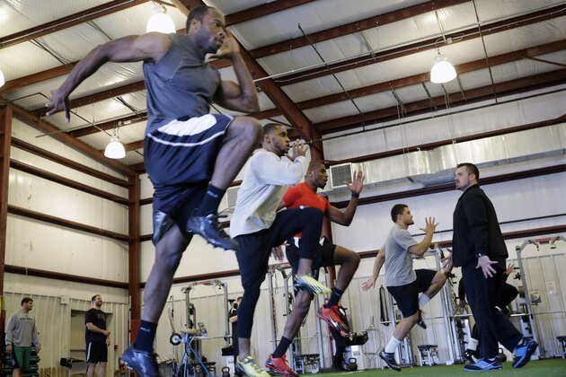 In this Feb. 14, 2014 photo, coach Geir Gudmundsen, right, looks on as players work on running techniques at TEST Sports Clubs in Martinsville, N.J. More than 300 NFL hopefuls will be measured on their 40-yard dash times, 225-pound bench press reps and other tests at the scouting combine in Indianapolis this week. Many college players get crash courses in everything from improving their performance in the physical tests to preparing for the intelligence at training centers like TEST Sports Clubs.  (AP Photo/Mel Evans)
