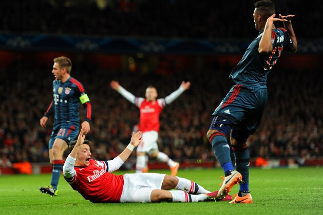 LONDON, ENGLAND - FEBRUARY 19:  Jerome Boateng of Bayern Muenchen brings down Mesut Oezil of Arsenal in the area for a penalty during the UEFA Champions League Round of 16 first leg match between Arsenal and FC Bayern Muenchen at Emirates Stadium on February 19, 2014 in London, England.  (Photo by Shaun Botterill/Getty Images)