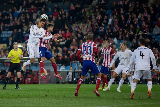 MADRID, SPAIN - FEBRUARY 11: Raphael Varane of Real Madrid CF wins the header after Diego Ribas of Atletico de Madrid during the Copa del Rey semi-final second leg match between Club Atletico de Madrid and Real Madrid CF at Vicente Calderon Stadium on February 11, 2014 in Madrid, Spain.  (Photo by Gonzalo Arroyo Moreno/Getty Images)